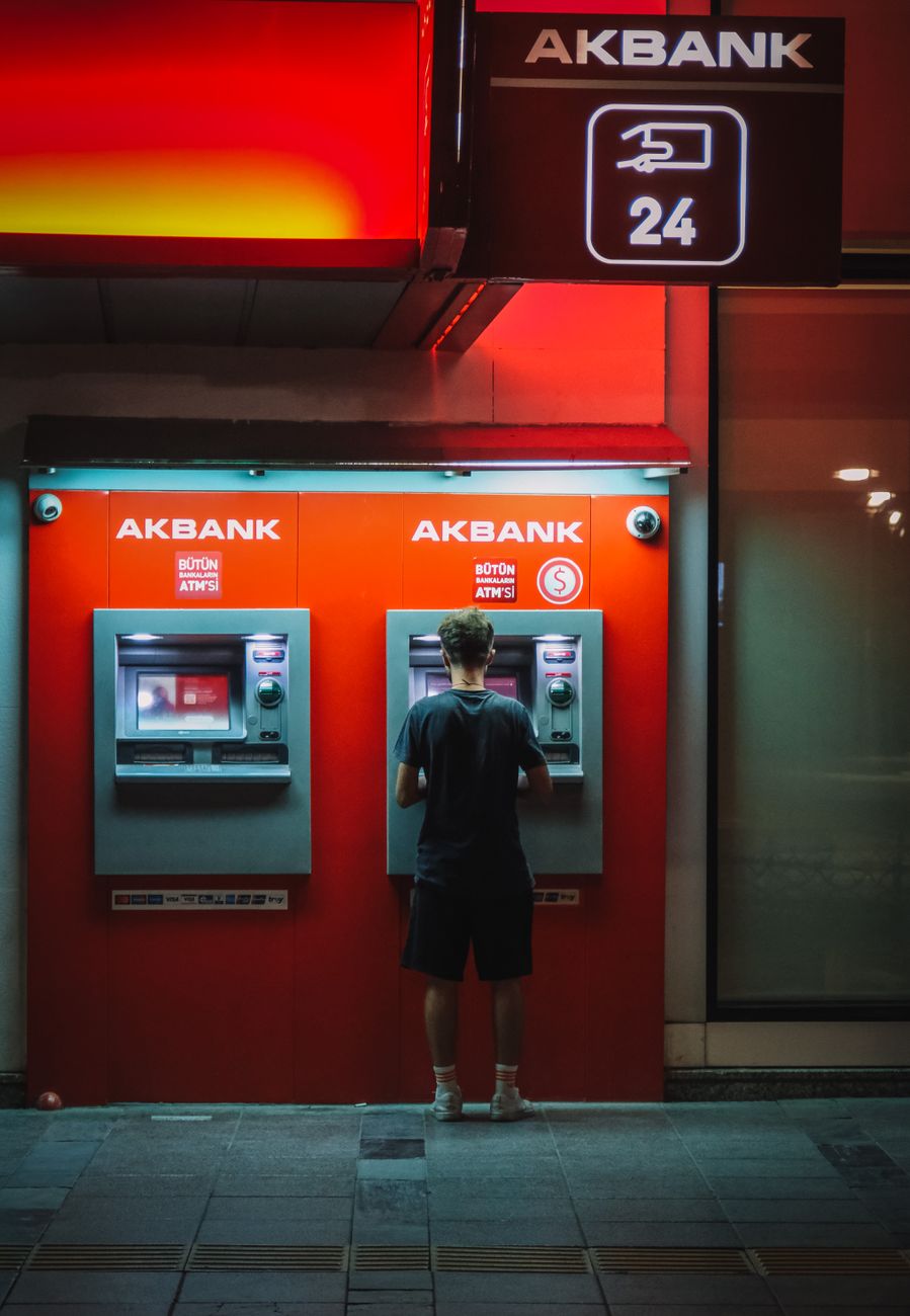man standing in front of a red cash dispenser